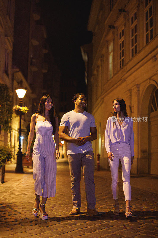 三个朋友晚上走在城市的街道上