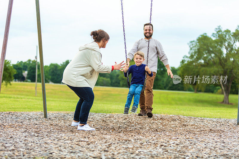 一对年轻夫妇和儿子像一家人一样在操场上玩得很开心