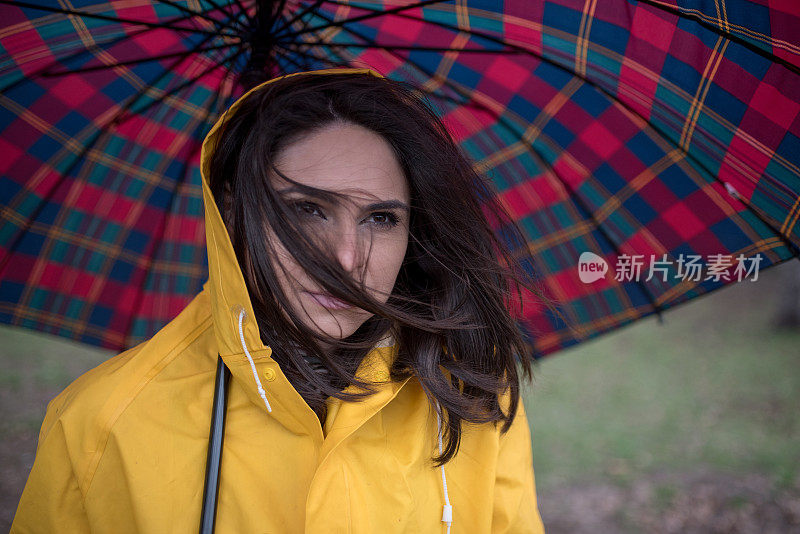 穿着黄色雨衣的年轻女子在公园里度过雨天