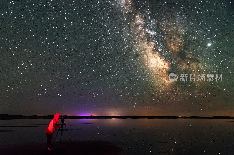 一位女摄影师正在拍摄银河，流星划过夜空