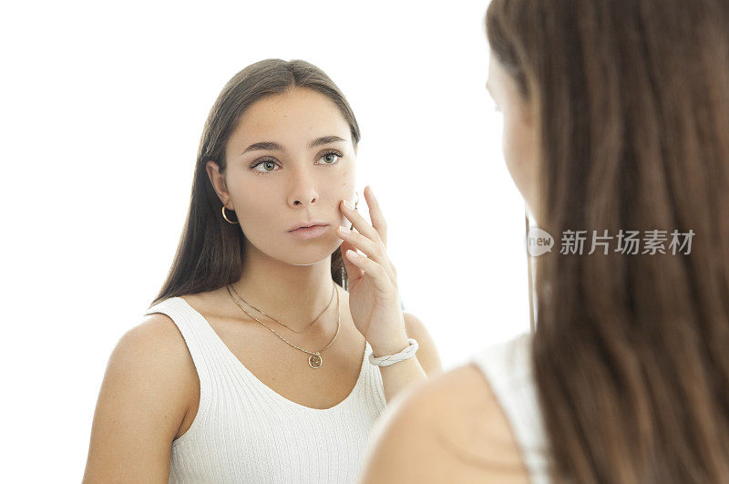 年轻女子在镜子前看她的痤疮疤痕