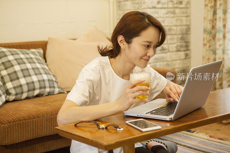 中年女人在客厅喝啤酒，用笔记本电脑