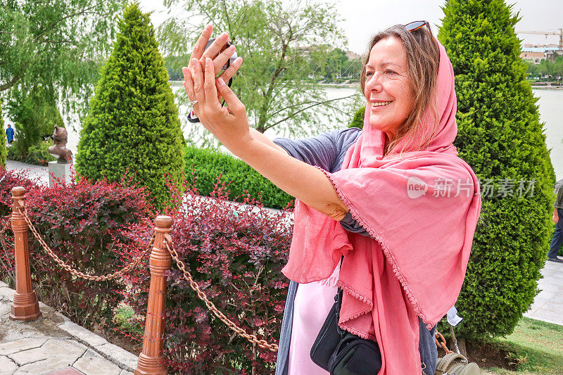微笑的女游客在伊斯法罕扎扬德河的河岸上自拍