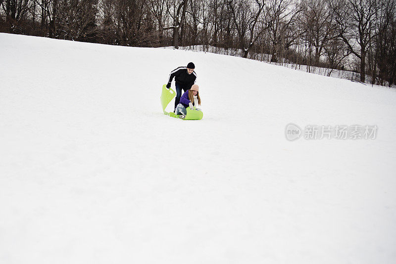 Z世代夫妇在雪天公园里滑下来。