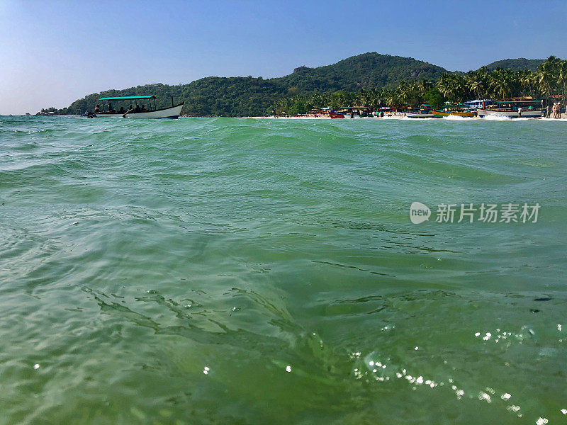 图片中的游船停泊在果阿海岸线上的海豚，海滩，蓝色的天空和蓝绿色的海，帕洛伦海滩，果阿，印度