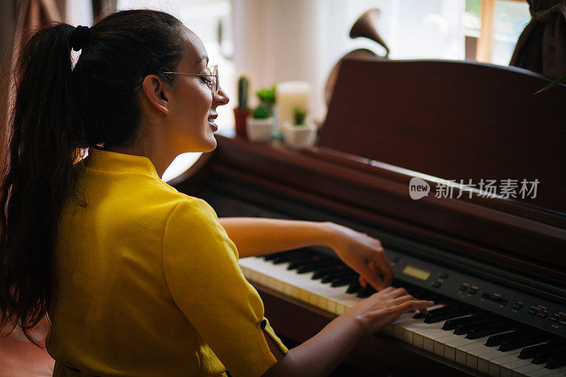 年轻的女钢琴家在自己家里的房间里谱曲