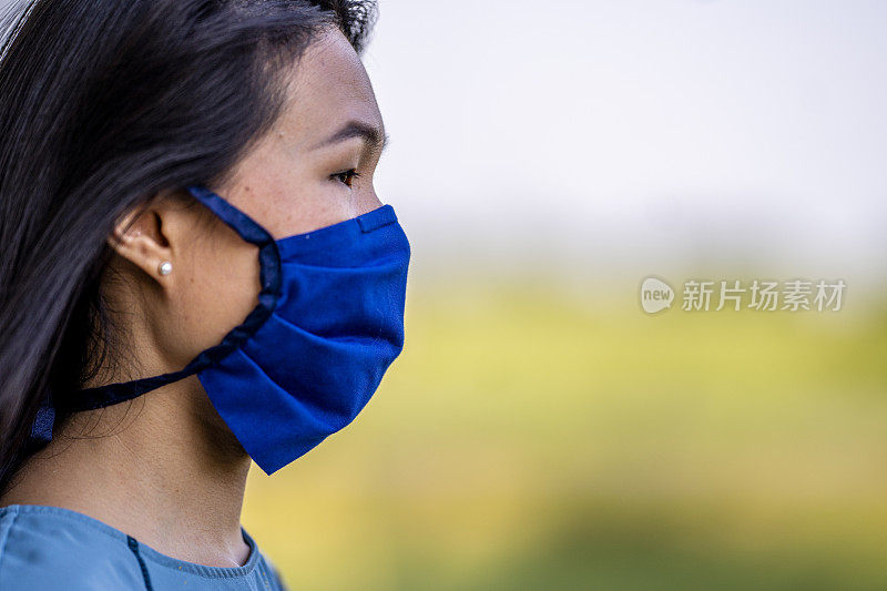 美丽的亚洲女人戴着可重复使用的防护面罩