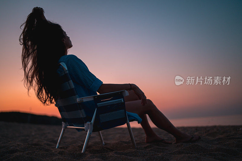 美丽的女人在日落的黄金时间在海滩上玩头发。户外的乐趣和友谊。