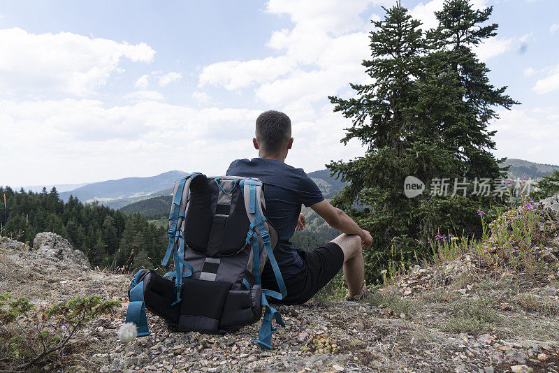 男人旅行者在山中放松独自旅行的生活方式概念多云的自然景观为背景