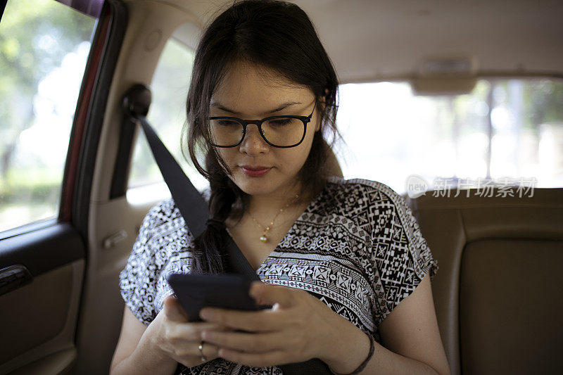 亚洲女性在乘出租车时使用手机