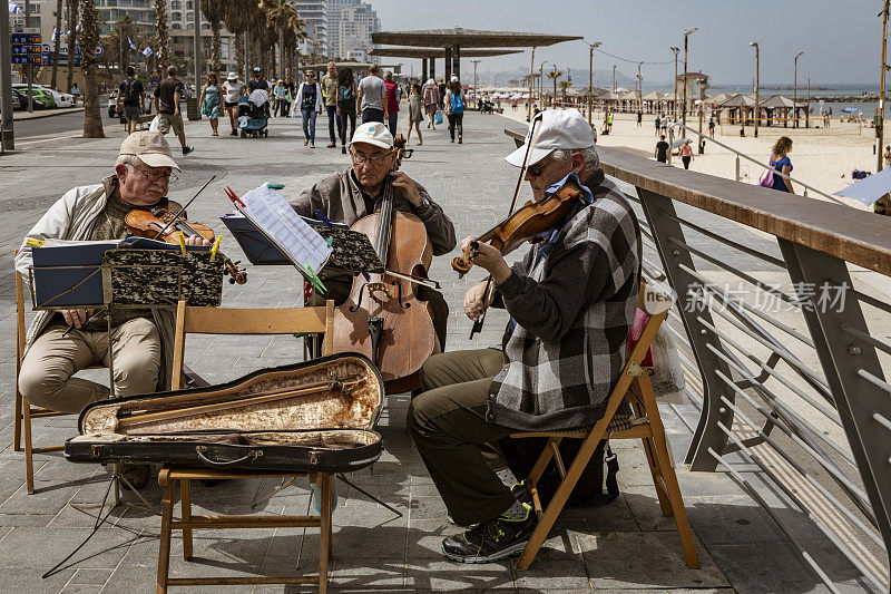 由老年男子组成的弦乐三重奏乐队在海滨木板路上玩耍
