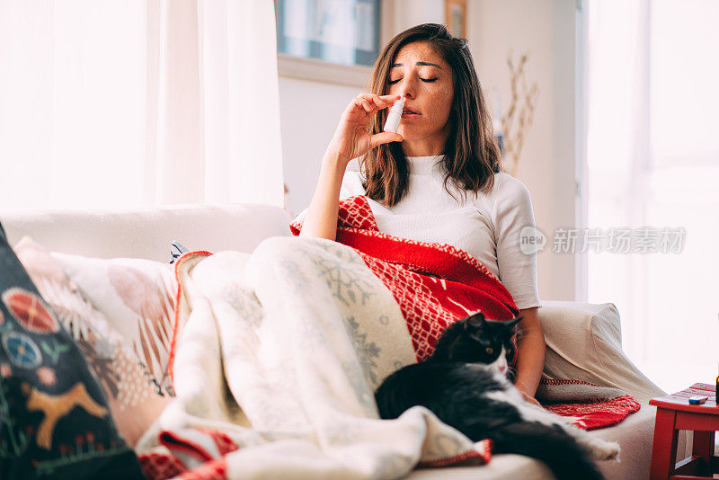 一个生病的女人和她的猫躺在沙发上