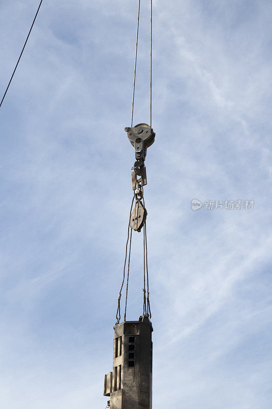 建筑起重机用大吊钩和工业用大铁钉吊在绳索上吊起，角度低
