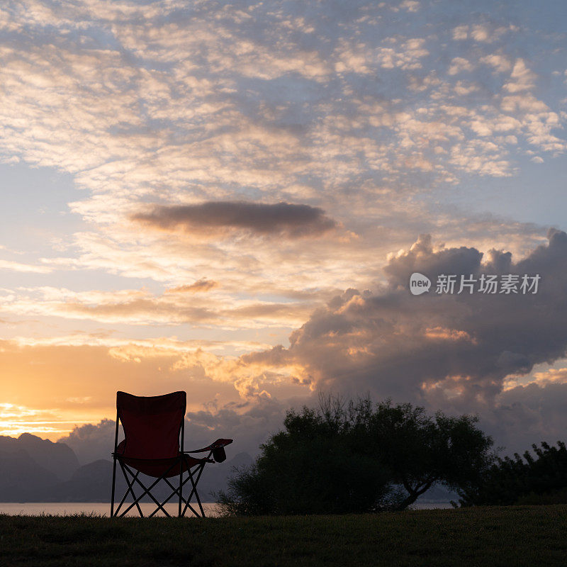 日落时海边露营椅的剪影