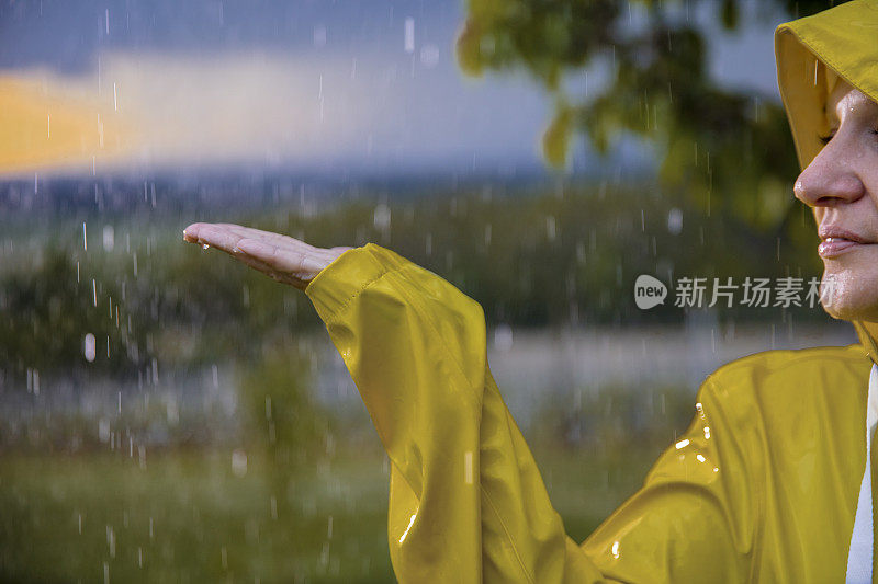 穿着黄色雨衣的快乐女人在享受雨