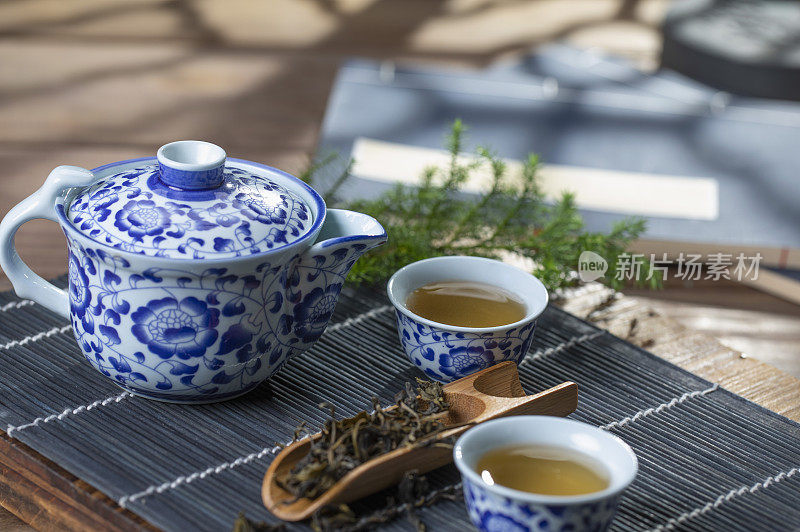 光影下的青花瓷中国茶壶和茶杯在竹简上