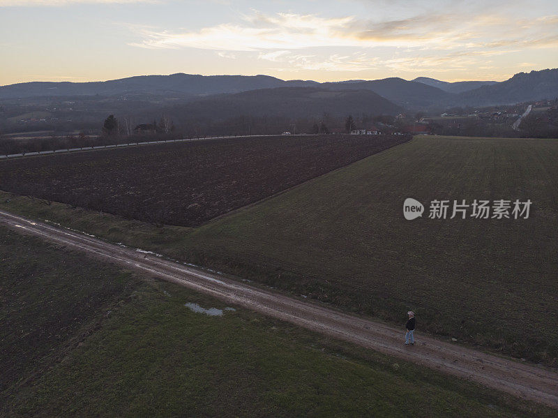 一个成年的农民在他的农场里在早春的时候耕种田地。鸟瞰图。