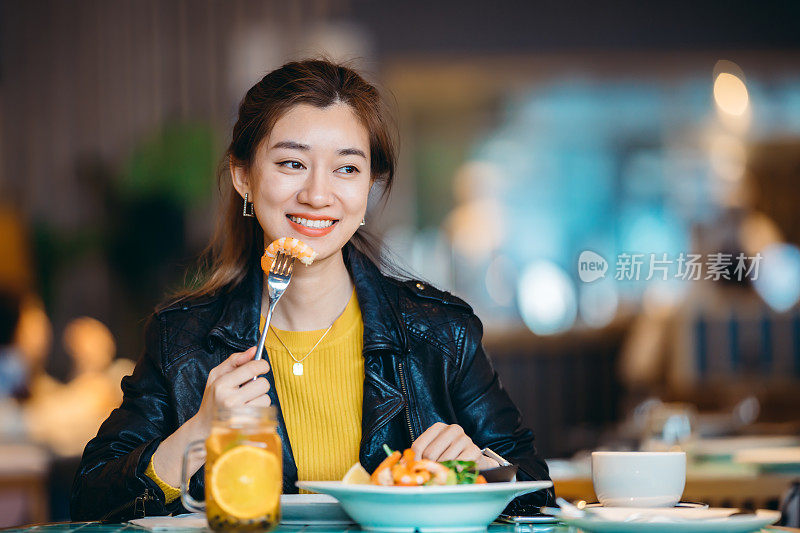 年轻的亚洲年轻女子在餐厅享受新鲜食物的肖像。