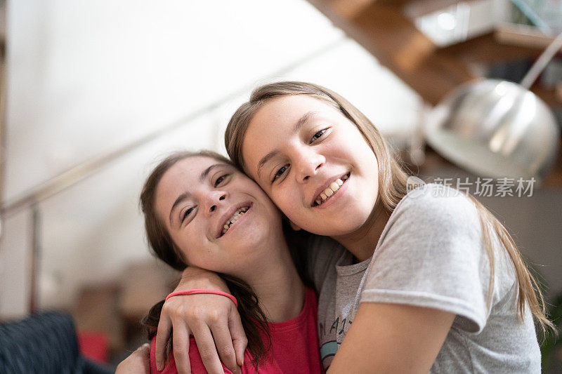 有特殊需要的女孩在家中拥抱姐妹的肖像