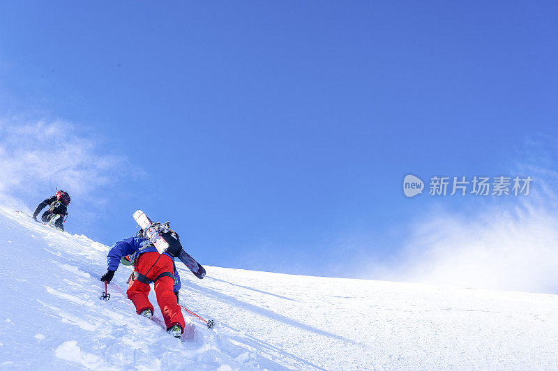 偏远地区的滑雪者攀登积雪的山坡