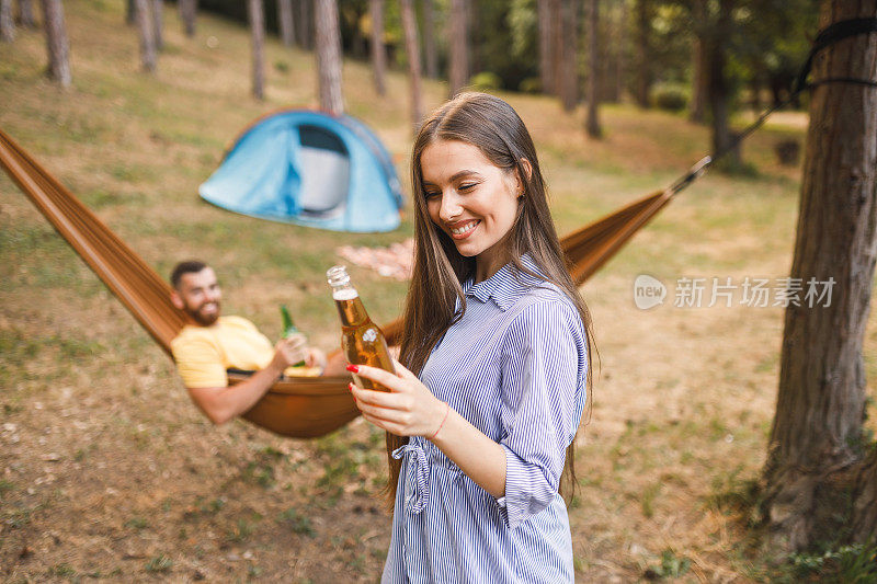 幸福的夫妇露营，有乐趣和喝啤酒的森林