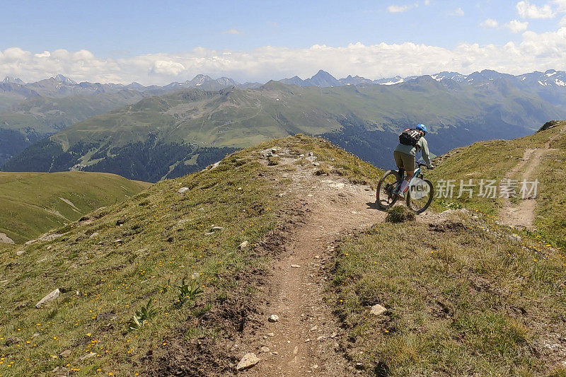 一名女子沿着阳光明媚的山脊骑山地车