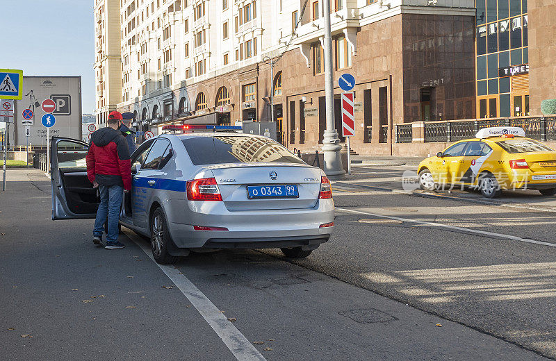出租车司机和交警在莫斯科市中心一辆警车附近