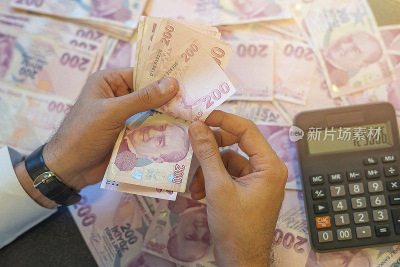 一个认不出来的人在数土耳其的钞票