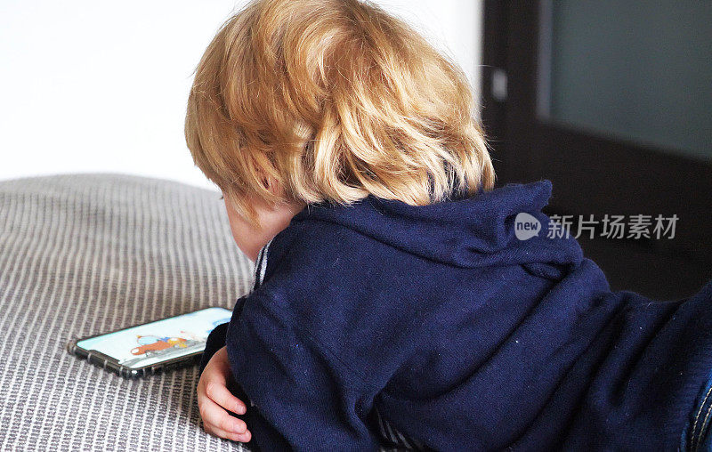 小男孩在床上玩智能手机