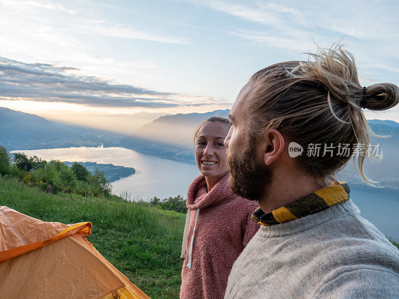 年轻人在山顶露营，欣赏湖景