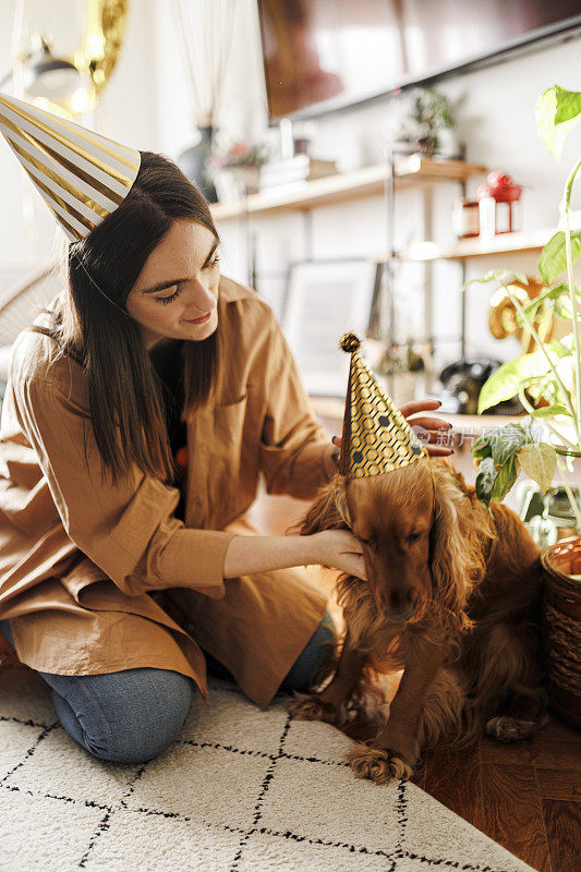美丽的女人和她的狗狗在家里庆祝她的狗狗生日。