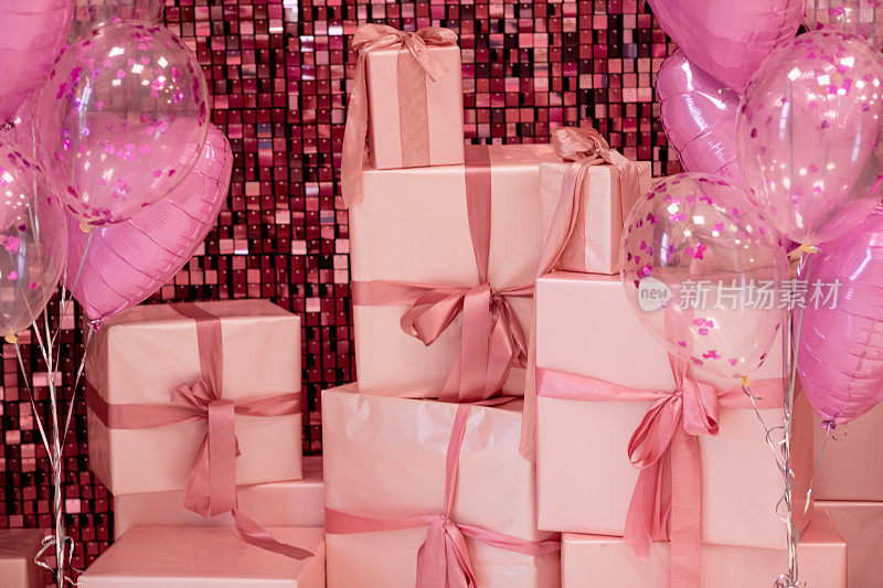 粉红色的礼品盒和气球在闪亮的粉红色背景上。节日的概念。妇女节，情人节，生日。