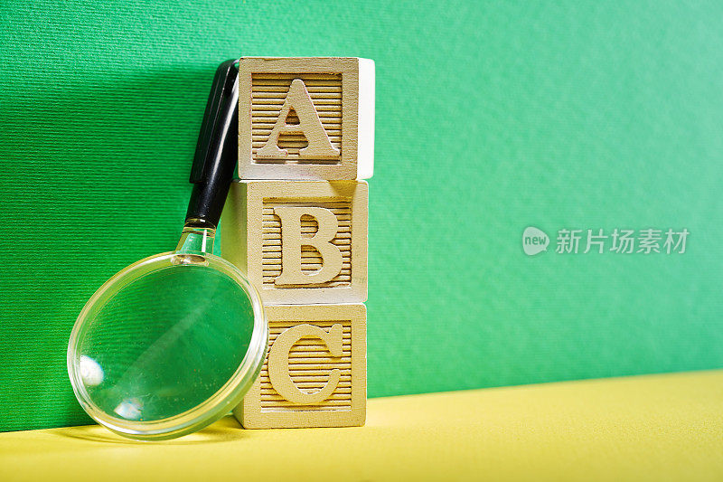 英文字母A、B、C，放大镜衬绿色背景