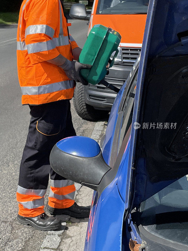 特写图像的蓝色汽车在路边抛锚，加油油箱与杰瑞可以燃料，车辆故障援助，汽车机械师穿着反光，高能见度的夹克