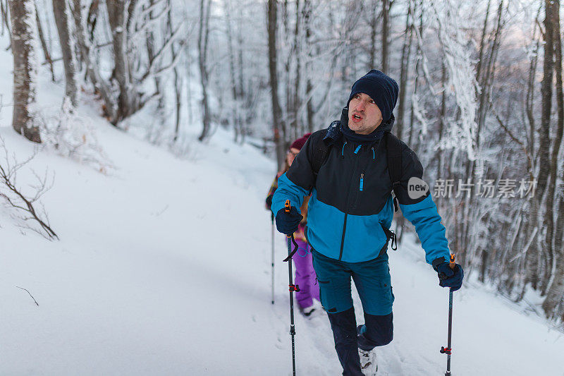 年轻英俊的男性徒步旅行者和他的女性朋友一起爬上雪山