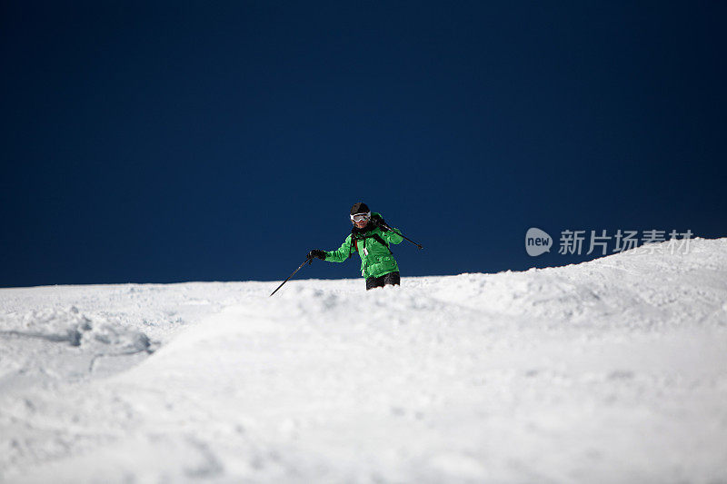 专业成熟的女子滑雪者在明亮的蓝色天际线。