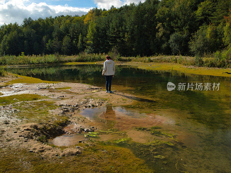 一名徒步旅行者在透明的泻湖上看着沙子上的泡泡。俯视图