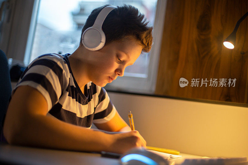 一个十几岁的男孩正在参加一个在线课程并做笔记。