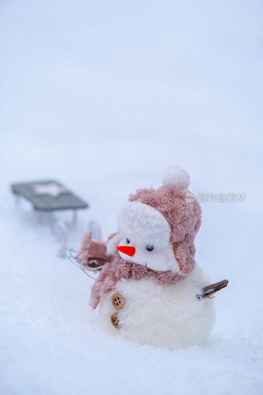 可爱的雪人玩具在雪地上拉雪橇。