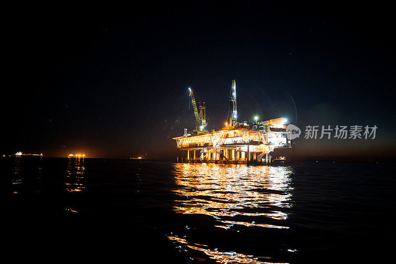 一张令人惊叹的照片展示了加利福尼亚州亨廷顿海滩海岸日落时的海上石油钻井平台。