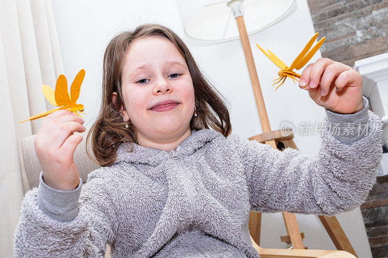 一个7岁的白人女孩正在用木制材料制作蜻蜓玩具。