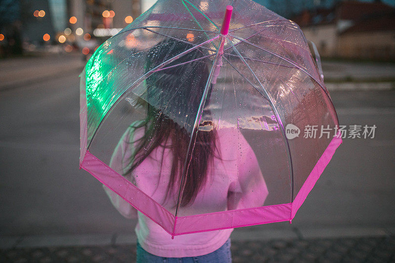 一个女人在雨夜撑伞行走的背影