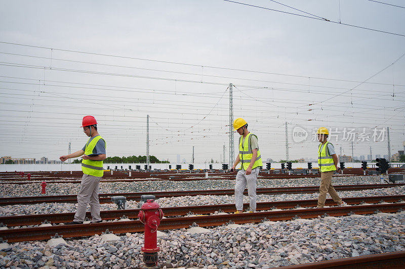 三个铁路工人在检查铁轨