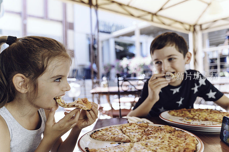 哥哥和妹妹在餐厅吃披萨。披萨。孩子的肖像