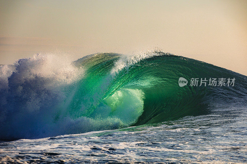 日出时，独特的海浪在金色的天空中破碎