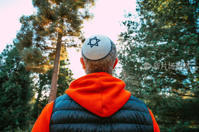 戴着圆顶小帽的犹太男子走在森林小路上