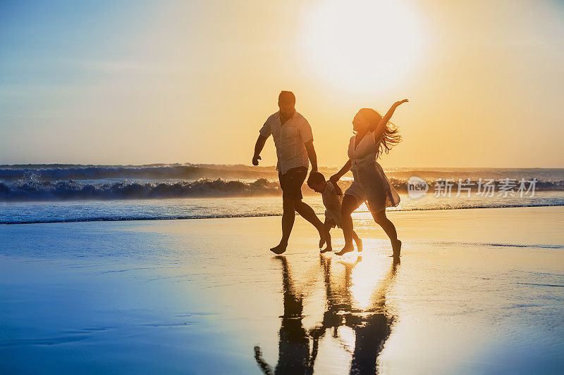 积极的家庭跑步与乐趣在日落海滩