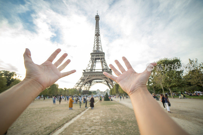 一位女士的手臂伸向法国巴黎的埃菲尔铁塔