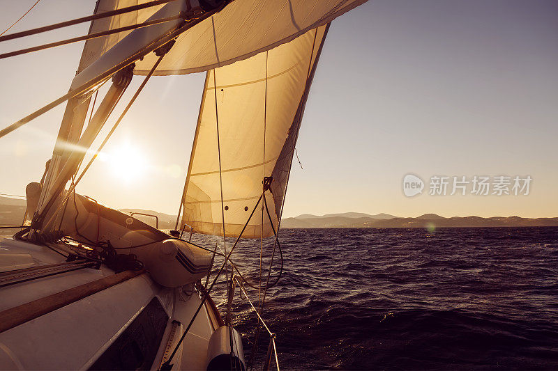 在日落海上的赛舟会期间，帆船扬起