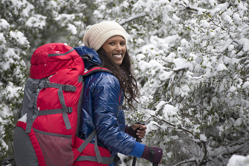 在白雪覆盖的森林里徒步旅行的女人。